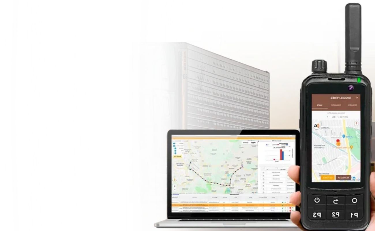 Un radio comunicador de uso rudo con GPS y una laptop con el panel de control de rastreo, frente a un camión de carga.