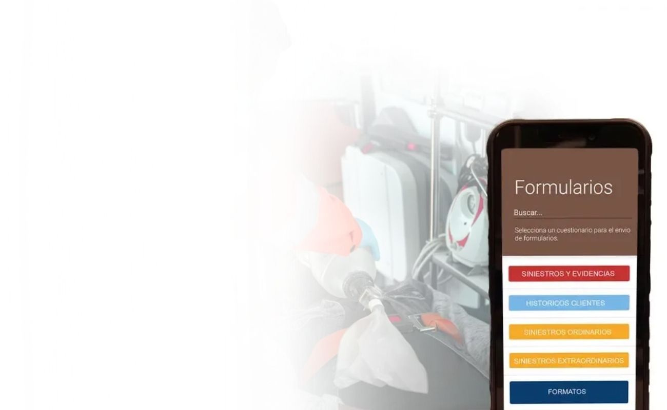 Radio de uso rudo con pantalla que muestra un formulario digital, en primer plano, con un paramédico atendiendo a un paciente en camilla en el fondo.