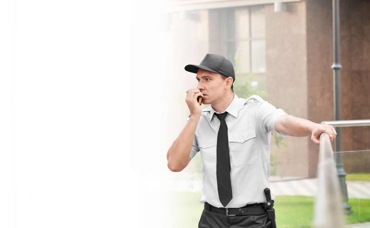Ingeniero o técnico de energía eólica usando un radio PTT para comunicarse, con un molino de viento de fondo, simbolizando el trabajo en zonas remotas.