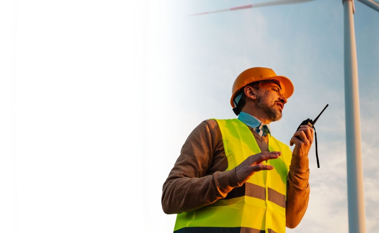 Operadores de seguridad privada usando un radio PTT y monitoreando cámaras de videovigilancia en un centro de control oscuro.