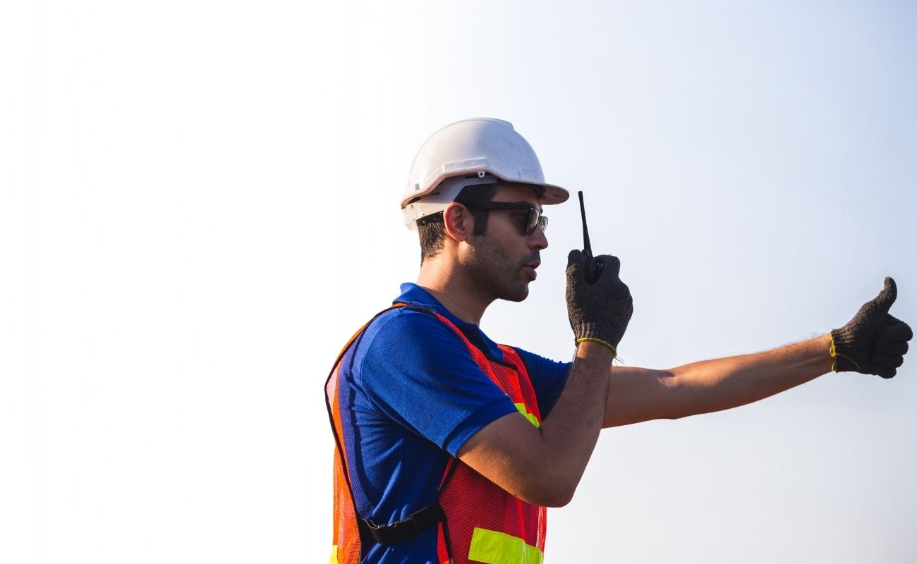 Operador industrial utilizando un radio PoC con plataforma PTT e inteligencia artificial para coordinación técnica en exteriores.