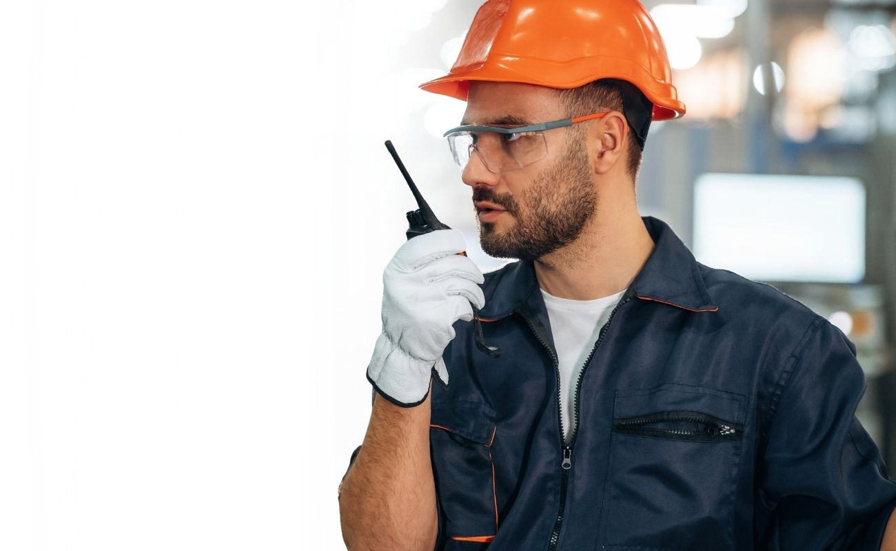 Trabajador industrial con equipo de seguridad utilizando un radio PoC con tecnología Zello Work para comunicación crítica.