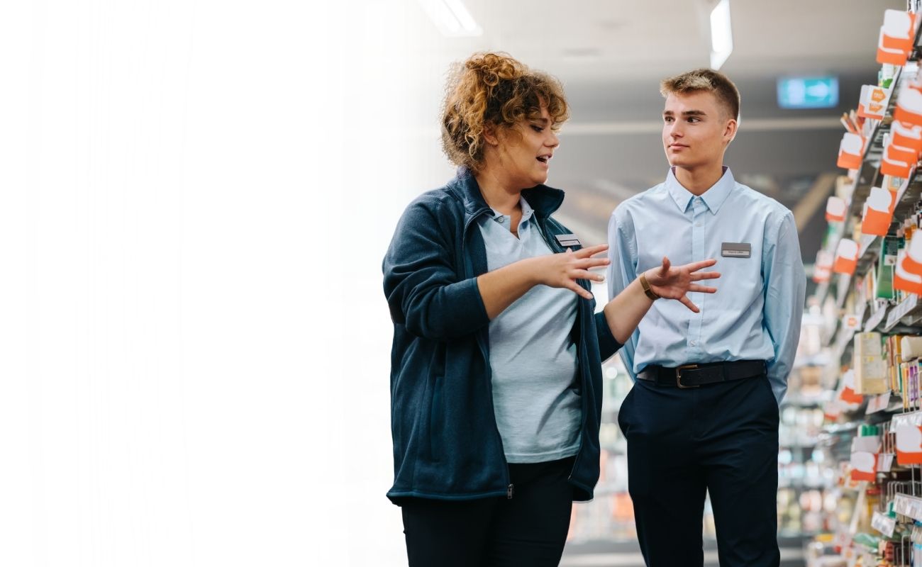 Gerente de primera línea interactuando con su equipo en un entorno operativo, ejemplificando la claridad y liderazgo mediante herramientas de IA de Zello.